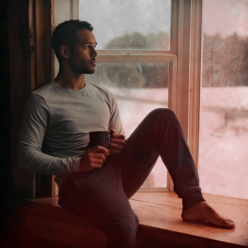 Person relaxing at home with soft red light glow in the background, representing natural IBS relief with red light therapy